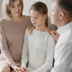 Parents comforting their daughter during a difficult conversation.