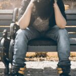 a man sitting with his head in his hands on a bench