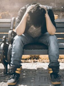 a man sitting with his head in his hands on a bench