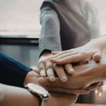 A group of people clasping hands representing team work
