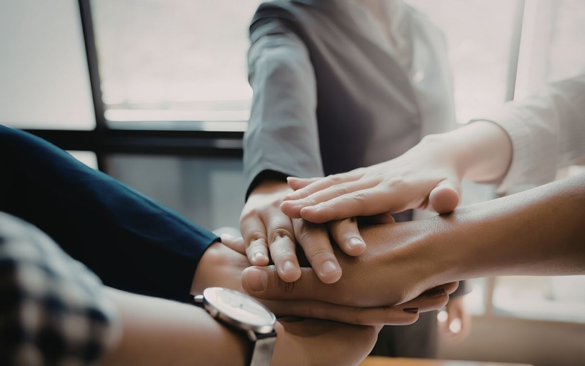 A group of people clasping hands representing team work