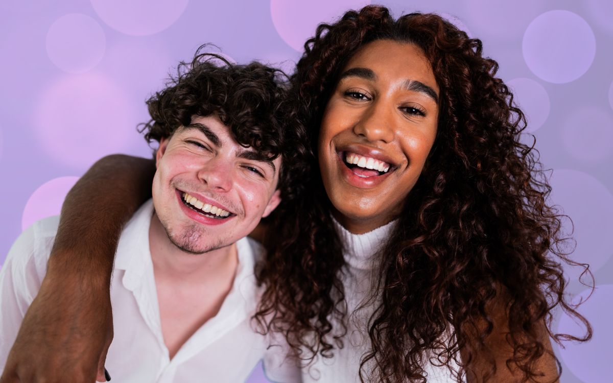 Two people smiling with a pink and purple background